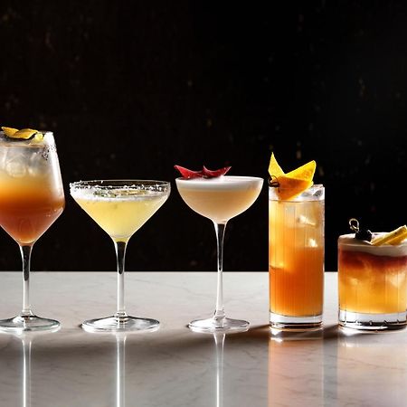 Middle Eight - Covent Garden - Preferred Hotels And Resorts Λονδίνο Εξωτερικό φωτογραφία The photo features a selection of five different cocktails lined up on a marble surface. Each drink is served in a distinct glass, showcasing a variety of colors and garnishes. 

1. The first cocktail is in a large wine glass, with a gradient color f