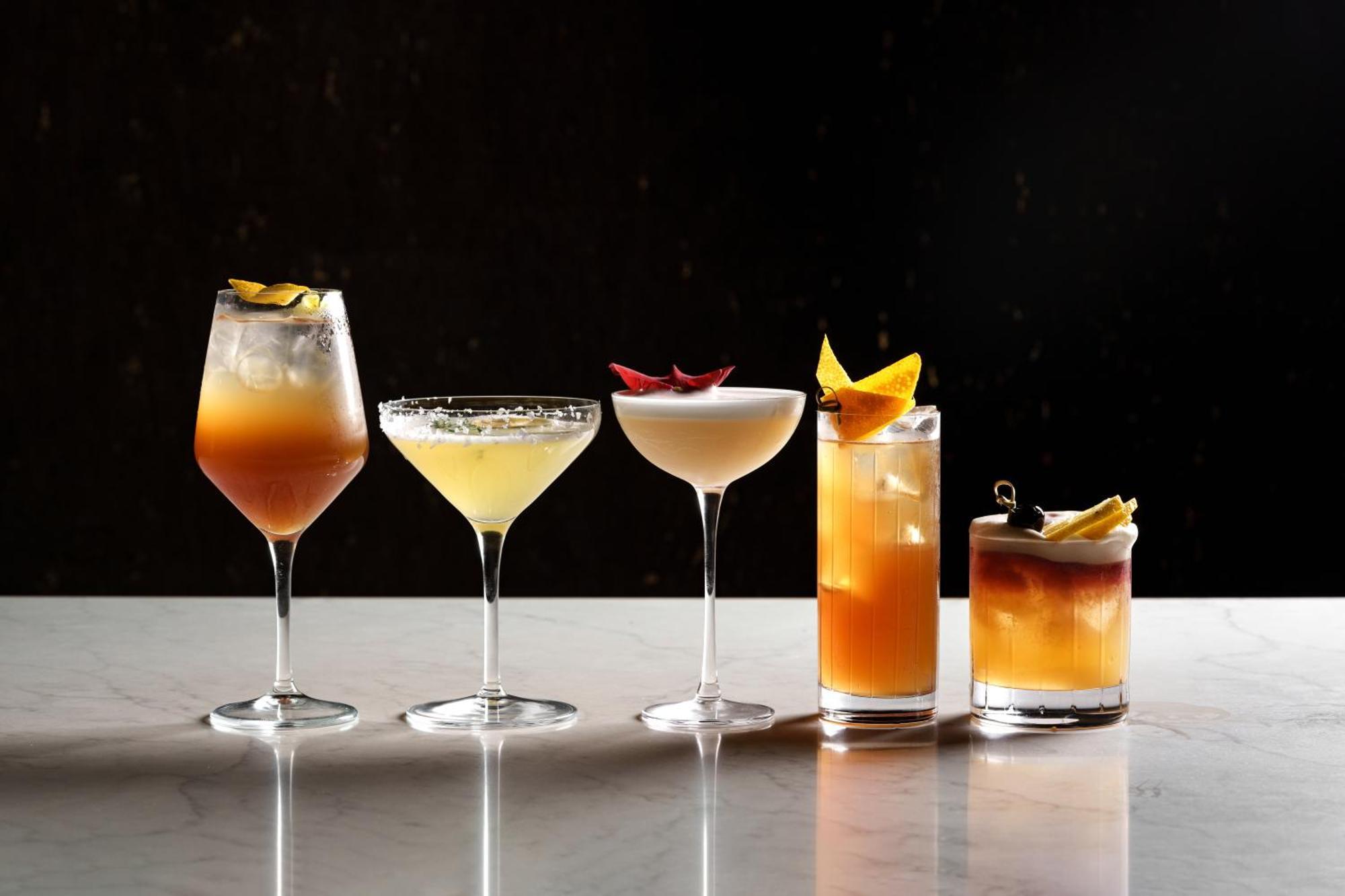 Middle Eight - Covent Garden - Preferred Hotels And Resorts Λονδίνο Εξωτερικό φωτογραφία The photo features a selection of five different cocktails lined up on a marble surface. Each drink is served in a distinct glass, showcasing a variety of colors and garnishes. 

1. The first cocktail is in a large wine glass, with a gradient color f