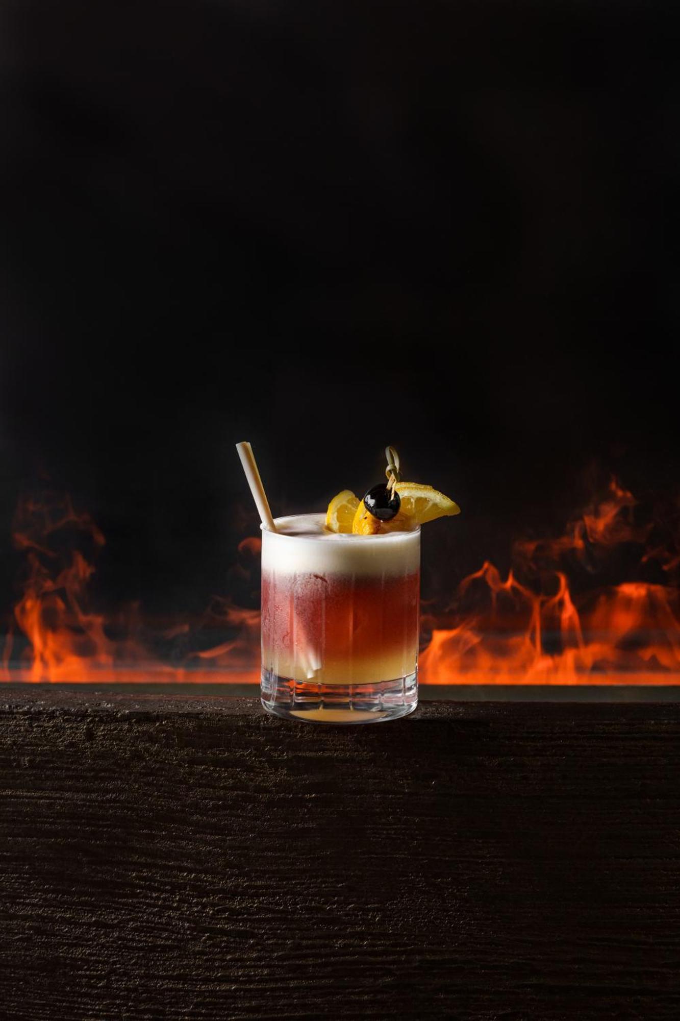 Middle Eight - Covent Garden - Preferred Hotels And Resorts Λονδίνο Εξωτερικό φωτογραφία The image shows a cocktail presented in a clear glass with a thick base. The drink features layered colors, transitioning from a deep reddish hue at the bottom to a lighter, frothy layer on top. It is garnished with a slice of lemon and a cherry, and